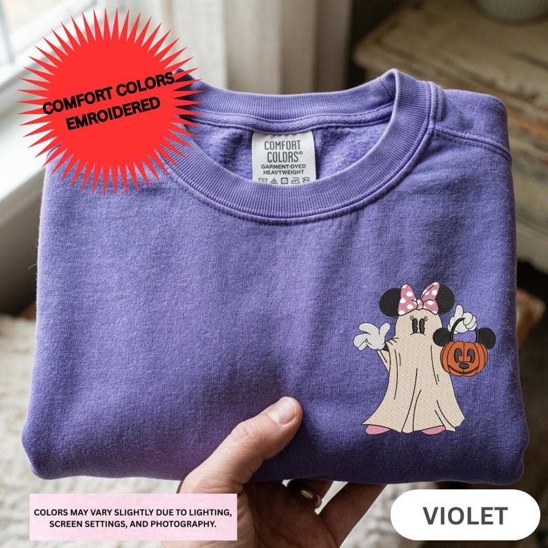 A purple t-shirt with a Minnie Mouse and a ghost character printed on it, along with a red starburst logo.