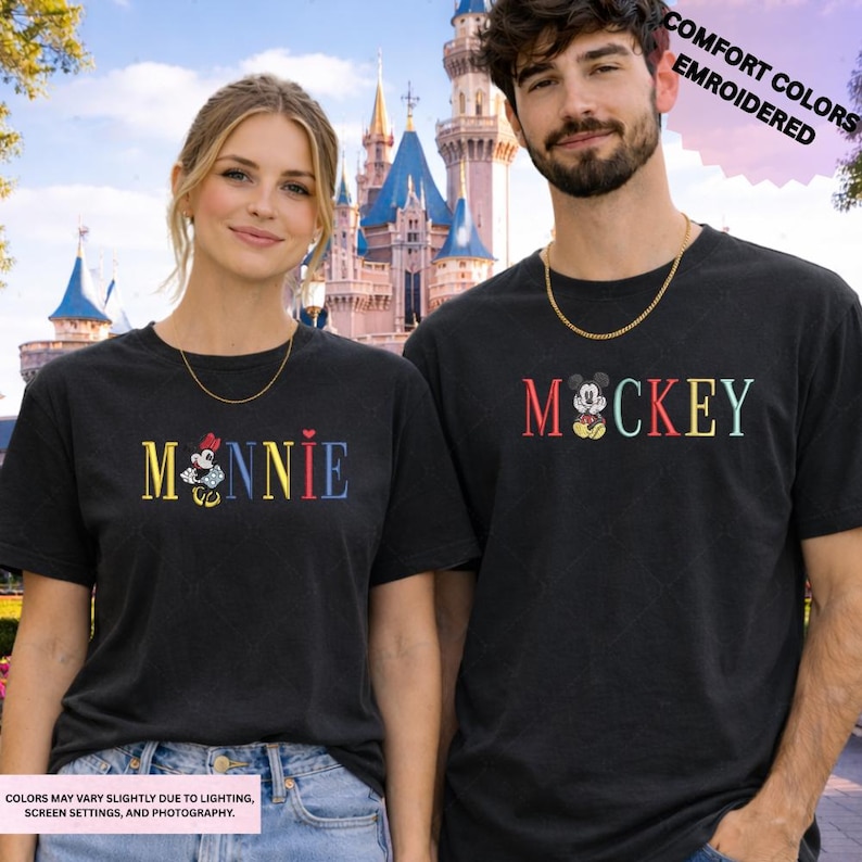 A man and a woman wearing matching t-shirts with the character Mickey Mouse printed on them, standing in front of a castle.