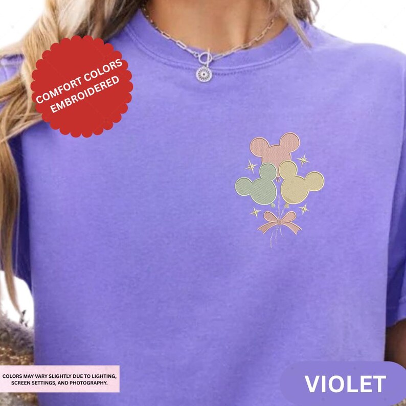 a close-up of a person wearing a purple t-shirt with a colorful embroidered design on the front.