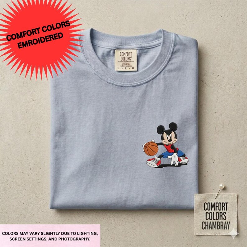 a gray t-shirt with a cartoon character of Mickey Mouse holding a basketball. The t-shirt is displayed on a flat surface, and there is a red starburst on the top left corner.