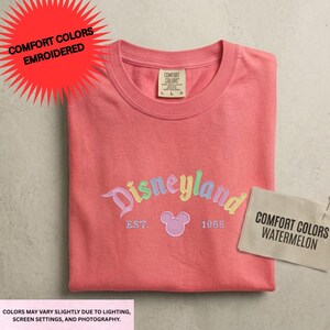 a pink t-shirt with the Disneyland logo and text, along with a tag that says "Comfort Colors" and a label that says "Comfort Colors Watermelon".