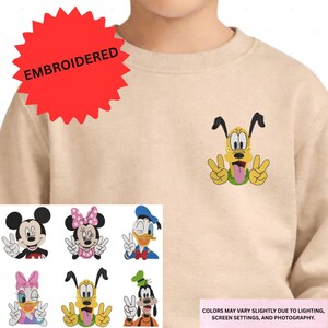 Embroidered characters on a beige sweater, including Minnie Mouse, Donald Duck, Goofy, Mickey Mouse, Donald Duck's friend, and Pluto.