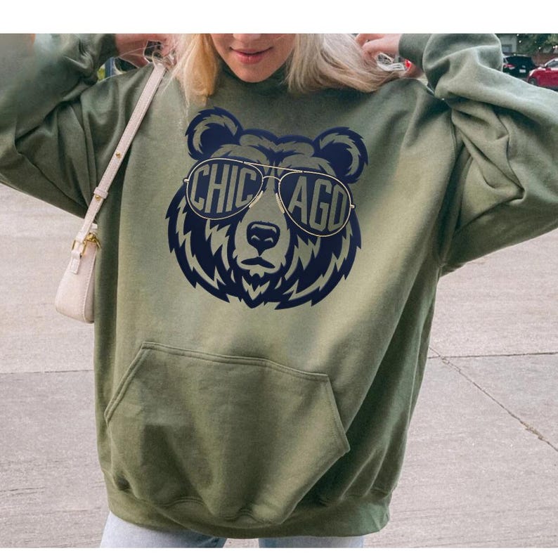 A woman wearing a green hoodie with a graphic of a bear wearing sunglasses and the text "CHICAGO" printed on it.