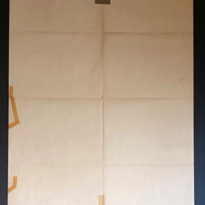 May include: A large, folded sheet of off-white paper with visible creases and tape. The paper is divided into eight rectangular sections. Brown tape secures the paper at the top, left, and bottom, with a small amount of text visible.