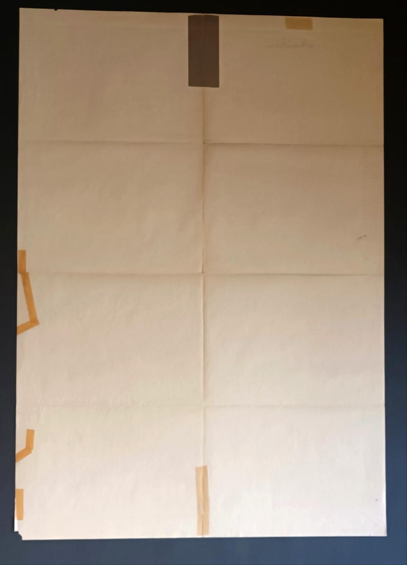 May include: A large, folded sheet of off-white paper with visible creases and tape. The paper is divided into eight rectangular sections. Brown tape secures the paper at the top, left, and bottom, with a small amount of text visible.