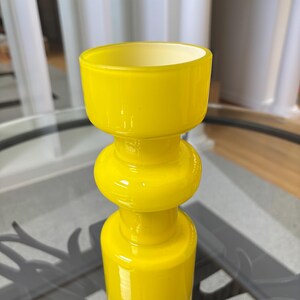 Peut inclure: Un vase en verre jaune vif avec un design empil&eacute; et bulbeux. Le vase a un large sommet ouvert et une section centrale arrondie, pos&eacute; sur une surface en verre transparent. La couleur vive et la forme unique du vase en font un &eacute;l&eacute;ment d&eacute;coratif.