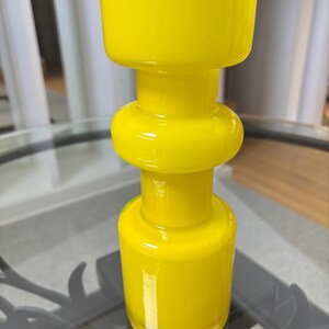 Peut inclure: Un vase en verre jaune vif avec un design unique et superpos&eacute;. Le vase pr&eacute;sente une base cylindrique, une section m&eacute;diane arrondie et un sommet carr&eacute;. La finition brillante refl&egrave;te la lumi&egrave;re, soulignant la couleur vibrante. Id&eacute;al pour la d&eacute;coration int&eacute;rieure.