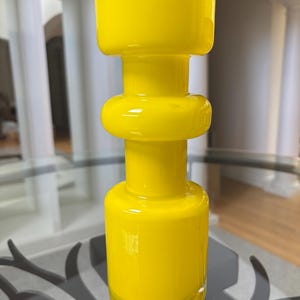 Peut inclure: Un vase en verre jaune vif avec un design unique et superpos&eacute;. Le vase a une base cylindrique, une section m&eacute;diane arrondie et un sommet plus large. La finition brillante refl&egrave;te la lumi&egrave;re, soulignant ses surfaces lisses et courbes. Cette pi&egrave;ce d&eacute;corative ajoute une touche de couleur.