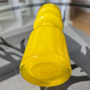 Peut inclure: Un vase en verre jaune vif avec une base arrondie et un corps cylindrique. Le vase pr&eacute;sente un motif textur&eacute; et tourbillonnant et un sommet bulbeux. La couleur jaune vif et la forme unique en font une pi&egrave;ce d&eacute;corative.