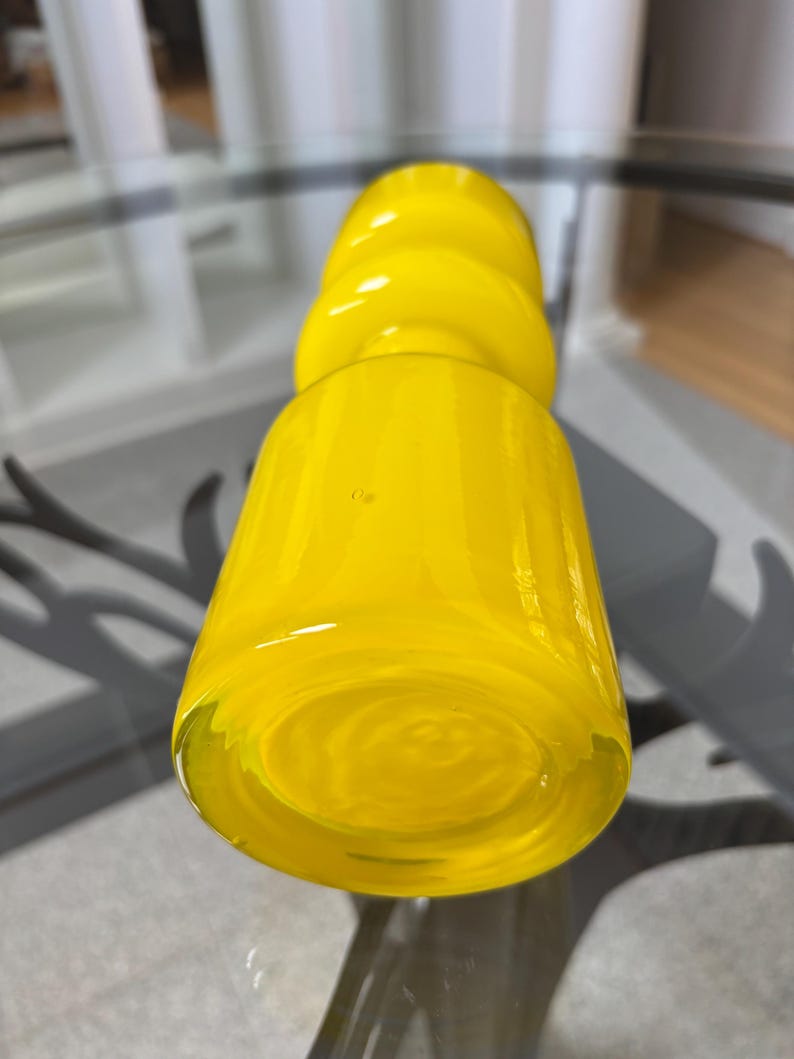 Peut inclure: Un vase en verre jaune vif avec une base arrondie et un corps cylindrique. Le vase pr&eacute;sente un motif textur&eacute; et tourbillonnant et un sommet bulbeux. La couleur jaune vif et la forme unique en font une pi&egrave;ce d&eacute;corative.