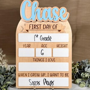 May include: Wooden first day of school sign with the name "Chase" in blue letters. The sign includes spaces to write "1st Grade", age, height, things they love, and "Soccer Player" for what they want to be.