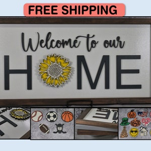 May include: A wooden sign with the words "Welcome to our HOME" in black lettering. A yellow sunflower with a black center is in the middle of the sign. The sign is framed in a dark brown wood frame.