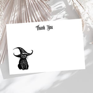 May include: A white card with the words "Thank You" in a gothic font. A black cat wearing a witch hat is illustrated on the lower left. The cat has large eyes and a fluffy appearance. The card is likely for Halloween or a similar theme.