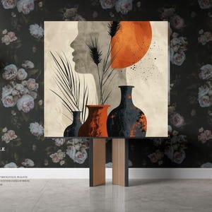 Puede incluir: Impresión de arte abstracto con un rostro estilizado, un gran sol naranja y tres jarrones en tonos marrones, naranja y negro. La impresión se muestra en una mesa consola con un fondo de papel tapiz floral.