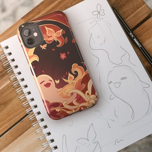 Pode incluir: Uma capa de telefone com um design colorido que apresenta um fantasma de desenho animado com um fundo floral. A capa tem um recorte para a câmera e um fundo preto.