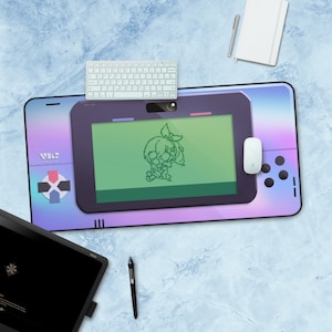 May include: A large, rectangular desk mat with a retro video game console design. The mat features a pixelated character on the screen, a D-pad, and buttons. A wireless keyboard and mouse sit on the mat, along with a notebook and pen.