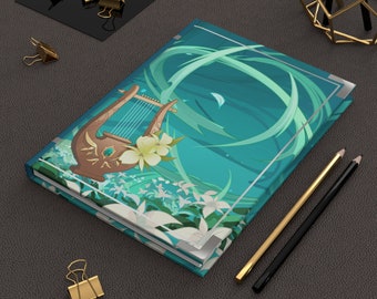 May include: A teal blue notebook with a white and green floral design and a gold lyre on the cover. The notebook is closed and lying on a gray surface.