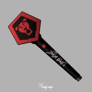 May include: A black and red light stick with a hexagonal head featuring a lion's head emblem. The handle is black with the text "Six Boys" in white script. A red dot is visible on the handle.