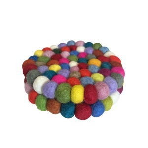 May include: A round, colorful coaster made of felt balls. The coaster features a variety of colors, including red, green, yellow, blue, and purple. The felt balls are tightly packed together, creating a textured surface. This coaster is a decorative and functional item.