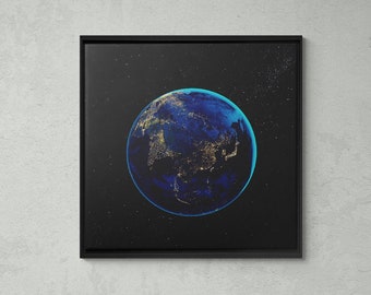 May include: A framed canvas print of a blue and white Earth with city lights, set against a black background with stars. The print is hanging on a gray wall in a home office setting.