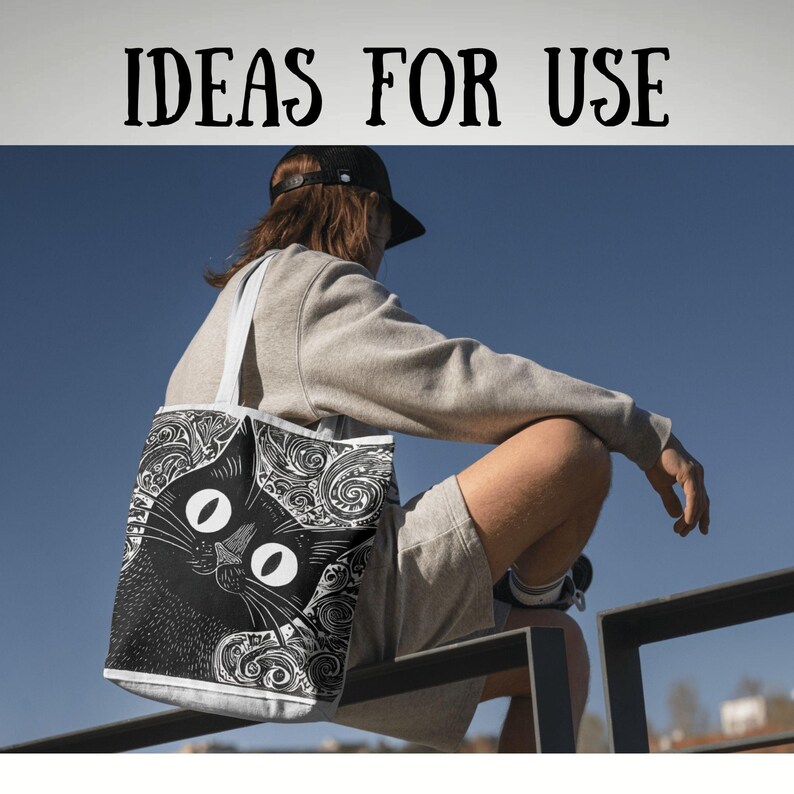May include: A black and white tote bag featuring a stylized cat design with large oval eyes and swirling patterns. The bag has white handles and the text "IDEAS FOR USE" at the top. The bag is carried by a person.