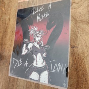 May include: A black and white illustration of a woman with pink hair holding a baseball bat. The background is red and black with the text "Live a Villain Die a Icon".