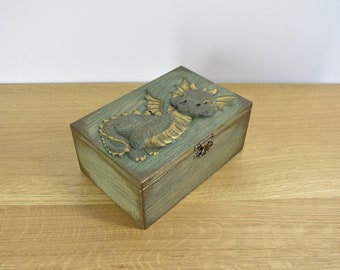 A wooden box with a carved dragon on the lid for storing jewelry and memories, photos and various trinkets.