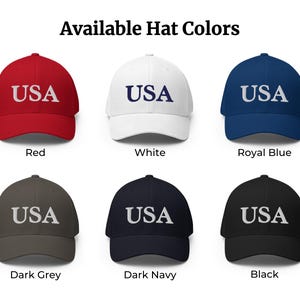 May include: Six baseball caps in red, white, royal blue, dark grey, dark navy, and black. Each cap features the text USA embroidered on the front. The image includes the heading Available Hat Colours and labels for each colour option below the caps.