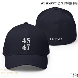 以下が含まれることがあります： 濃いネイビーブルーのFlexfit 6277ウールコームドキャップ。キャップの前面には白で「45」と「47」の数字が表示されています。キャップの背面には白で「TRUMP」の文字があります。The Great Trump Storeのロゴが下にあります。