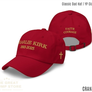Puede incluir: Gorra de béisbol color arándano con texto dorado. El frente muestra "HARLIE KIRK 1993-2025". La parte trasera dice "FAITH COURAGE" con una pequeña cruz. Correa ajustable. De The Great Trump Store.
