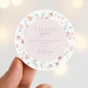 May include: A round sticker with a floral design and the text "Thank you" in a soft pink circle. The sticker also includes the text "For joining me at my baby shower" and the name "Kelsey".