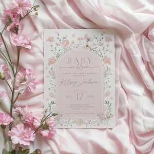 May include: A pink floral baby shower invitation with the text "Baby in Bloom" and the name "Kelsey Jackson". The invitation includes the date and time of the shower, as well as the address and RSVP information.