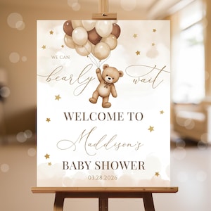Könnte beinhalten: Ein weißes Willkommens-Schild mit goldenen Sternen und einem Teddybär, der braune und beigefarbene Ballons hält. Das Schild lautet "We can barely wait" und "Welcome to Madison's Baby Shower 03.28.2026".