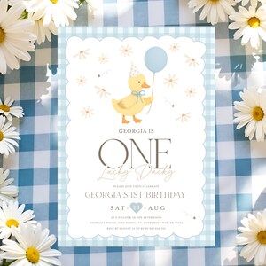 May include: A light blue and white gingham patterned birthday invitation with a scalloped edge. The invitation features a yellow duck holding a blue balloon, with the text "GEORGIA IS ONE Lucky Ducky". The invitation is for Georgia's 1st birthday.