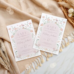 May include: Two pink and white floral baby shower invitations with the text "Baby in Bloom" and "Join us for a baby shower honoring Kelsey Jackson" on each. The invitations are decorated with a floral arch and have a pink background.