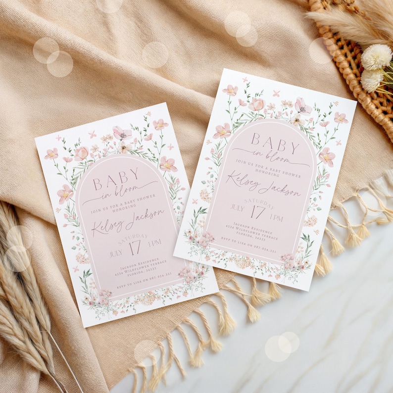 May include: Two pink and white floral baby shower invitations with the text "Baby in Bloom" and "Join us for a baby shower honoring Kelsey Jackson" on each. The invitations are decorated with a floral arch and have a pink background.