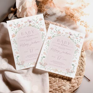 May include: A pink and white baby shower invitation with floral illustrations and the text "Baby in Bloom" and "Kelsey Jackson". The invitation includes the date and time of the event, "Saturday, July 17, 1 PM".