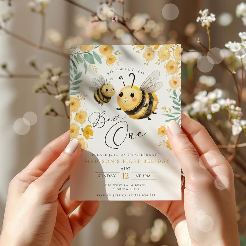 Op de afbeelding: Een gele en zwarte bij met een hartje op zijn lichaam en de tekst "Bee One" op een witte achtergrond met gele bloemen en groene bladeren. De tekst hieronder luidt "Doe mee met ons om Madisons eerste bijendag te vieren. Zondag 12 augustus om 15:00 uur. 101 West Palm Beach, Florida 33101. RSVP naar Jessica op 987.654.321."