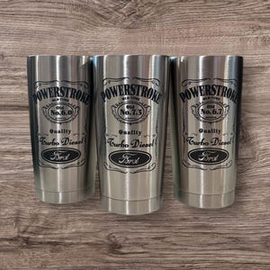 May include: Three stainless steel tumblers with black text and logos. The tumblers feature the text "POWERSTROKE" with the words "Old Time" and "Quality Turbo Diesel" below. Each tumbler has a different number: "No. 6.0", "No. 7.3", and "No. 6.7". The word "Ford" is printed below the number on each tumbler.