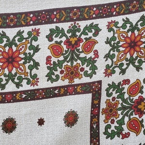Peut inclure: Un tissu blanc avec un motif floral brun, vert, rouge et jaune. Le tissu a un motif répétitif de fleurs et de feuilles.