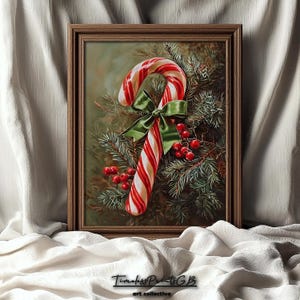 May include: A framed print depicting a candy cane with red and white stripes, a green bow, and red berries, set against evergreen branches. The frame is a warm brown colour. A festive Christmas-themed artwork.