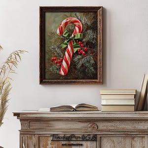 May include: A framed print of a candy cane with red and white stripes, a green bow, and red berries. The artwork is set against evergreen branches. The frame is dark brown. The print is displayed on a white wall, above a wooden cabinet.