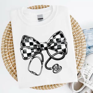 May include: White t-shirt featuring a black and white chequered bow tie and a stethoscope design.