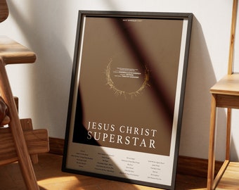 May include: A framed poster with a brown background and gold accents. The poster features the title "Jesus Christ Superstar" and a list of songs from the musical.