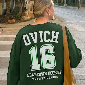 May include: Green sweatshirt with white text that says "OVICH 16" and "BEARTOWN HOCKEY VARSITY LEAGUE" on the back.