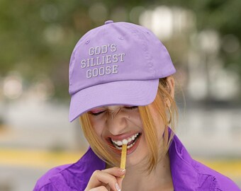 May include: A purple baseball cap with the text "GOD'S SILLIEST GOOSE" embroidered in white. The cap is worn by a person who is smiling and eating a french fry.