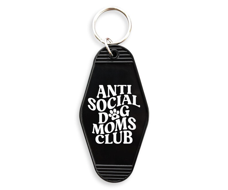 May include: Black motel key chain with the text "Anti Social Dog Moms Club" in white lettering. The key chain features a paw print graphic.