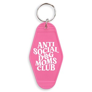 May include: Pink motel key chain with the text "Anti Social Dog Moms Club" in white lettering.