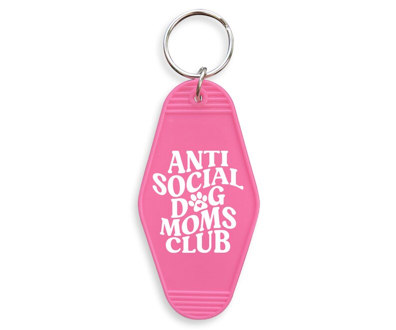 May include: Pink motel key chain with the text "Anti Social Dog Moms Club" in white lettering.