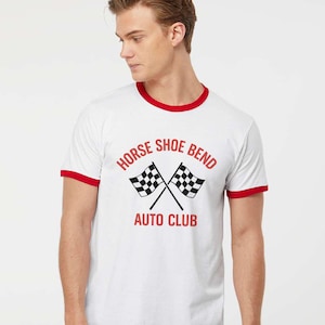 May include: White t-shirt with red trim featuring the text "HORSE SHOE BEND AUTO CLUB" and crossed checkered flags. The shirt has a classic ringer style with red accents on the collar and sleeves.